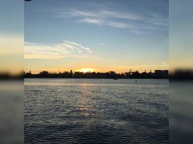 A serene sunset view over the water, featuring a boat in the distance — perfect for capturing tranquil moments on the water.