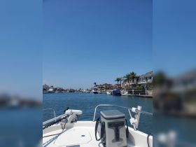 A scenic view from the front of a boat navigating through a tranquil waterway lined with luxurious homes and palm trees, perfect for a relaxing day on the water.