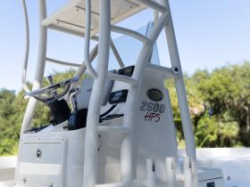 Close-up view of the helm and console of a boat, showcasing the steering wheel and navigation equipment, ideal for fishing or cruising adventures.