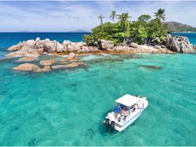 A vibrant scene of a group enjoying snorkeling near a picturesque island, with clear turquoise waters and rocky formations creating a stunning backdrop.