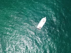 Aerial view of a boat gliding through vibrant turquoise waters, showcasing the beauty of a day on the sea.