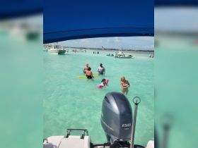 A fun-filled day at the beach with families enjoying swimming and playing in the shallow turquoise waters, perfect for a summer outing.