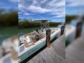 A side view of a Pioneer center console boat docked in calm waters, showcasing its sleek design and spacious seating — perfect for fishing or day trips.