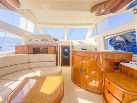 A spacious and elegantly designed interior of a yacht featuring comfortable seating and a well-equipped helm, perfect for relaxing and navigating on the water.