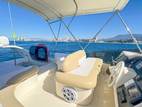 A well-appointed helm area of a boat, featuring comfortable seating and a clear view of the water and skyline, perfect for navigating the seas.