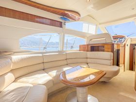 Interior view of a luxurious yacht cabin featuring comfortable seating and a helm area, perfect for relaxing and enjoying the scenic views while on the water.