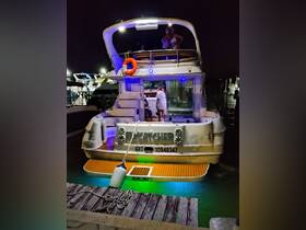 A lively group enjoys a night out on a boat, illuminated by colorful lights, creating a festive atmosphere perfect for celebrations on the water.