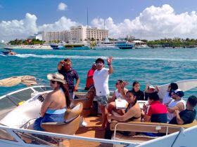 A lively group enjoys a boat party on the ocean, capturing fun moments and celebrations with friends against a vibrant backdrop of the coastline.