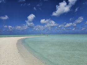 A stunning view of a serene beach with turquoise waters and a lone figure enjoying the picturesque coastline — an ideal destination for relaxation and exploration.