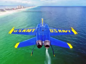 An aerial view of a U.S. Navy aircraft flying over turquoise waters, showcasing the stunning coastal scenery.