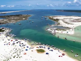 A vibrant scene at a popular sandbar, filled with boats and beachgoers enjoying the sun and water activities — a perfect destination for summer fun.