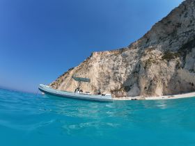 A sleek speedboat anchored in crystal-clear turquoise waters, framed by stunning cliffs — an ideal setting for a day of exploration and adventure.