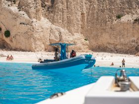 A vibrant scene featuring a boat anchored near a beautiful beach, with people enjoying the sun and swimming in the turquoise waters — a perfect summer getaway.