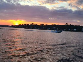 A scenic sunset view with a boat cruising across the water, capturing the beauty of evening adventures on the water.