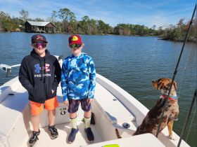 Two boys enjoy a sunny day on the boat with their dog, capturing the essence of outdoor fun and adventure on the water.