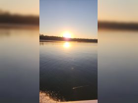 A serene sunset view over calm waters, with a distant boat silhouetted against the vibrant sky — perfect for capturing the tranquility of evening boat rides.