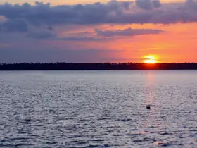 A stunning sunset over tranquil waters, creating a picturesque scene perfect for evening boat trips or romantic getaways.