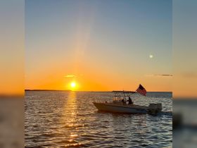 A boat cruises through shimmering waters at sunset, creating a picturesque scene perfect for evening adventures on the water.
