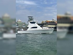 A sleek yacht cruising through the water, showcasing its elegant design and structure against a vibrant backdrop of waterfront buildings.