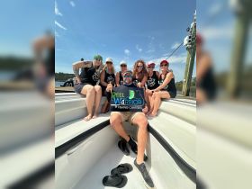A lively group of friends celebrates their fishing charter aboard a boat, showcasing camaraderie and adventure on the water.
