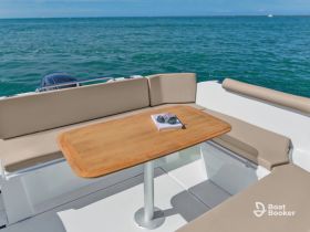 A cozy seating area inside a boat featuring a wooden table and a scenic view of the water, perfect for relaxing or dining while on the water.