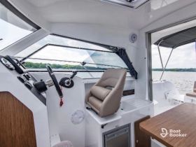A sleek view of the helm area inside a modern boat, showcasing the console and seating — perfect for navigating the waters in style.