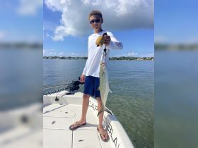 A young boy proudly displays his catch while fishing on a boat, showcasing the excitement of a successful day on the water.