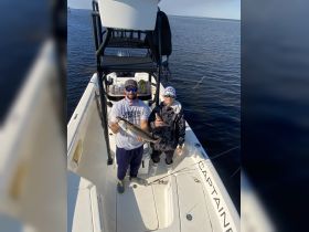A proud moment as a man and a child display their catch while fishing on a boat — a perfect family adventure on the water.