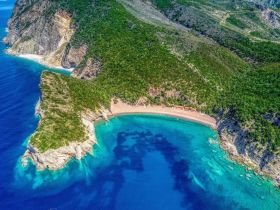 A stunning aerial view of a secluded beach surrounded by lush greenery and crystal-clear waters, perfect for exploring hidden gems on a boating adventure.