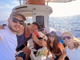 A cheerful group of friends enjoys a fun day on the boat, capturing memories with smiles and camaraderie against a sparkling ocean backdrop.