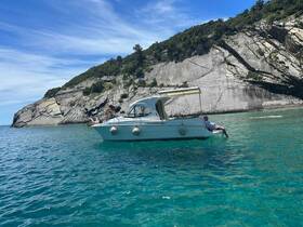 A group enjoys a sunny day on a boat, relaxing by the stunning coastline and clear turquoise waters — perfect for summer adventures.