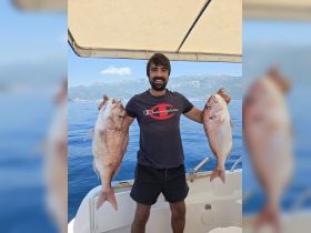 A proud angler displays his impressive catch of two fish while enjoying a day on the water, showcasing the thrill of fishing adventures.