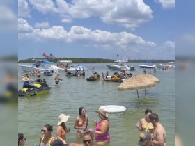 A lively gathering at a sandbar with guests enjoying swimming, jet skiing, and drinks under the sun — the perfect summer party atmosphere.