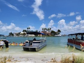 A lively group enjoys a sandbar stop with pontoon boats, soaking up the sun and fun in the water — the perfect setting for a day of relaxation and celebration.