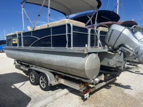 A sleek pontoon boat named 'Manitru' is docked and ready for adventure, showcasing its stylish design and powerful Honda engine.