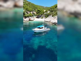 A scenic view of a boat anchored in crystal-clear waters, with a beautiful beach and lush greenery in the background — perfect for exploring hidden coves and enjoying nature.