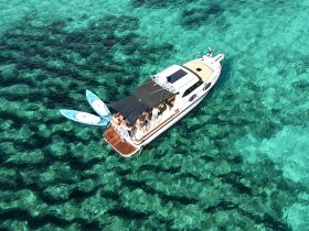 A vibrant scene featuring a group enjoying paddleboarding from a boat in crystal-clear waters, perfect for summer adventures and water sports.