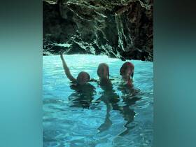 Three children joyfully swim in a stunning cave pool, capturing the essence of adventure and fun in a unique natural setting.