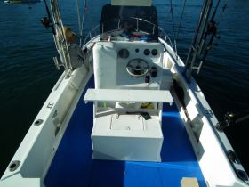 An interior view of a fishing boat's helm area, featuring a steering console and seating, perfect for a day out on the water.