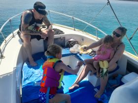 A family enjoys a sunny day on the boat, sharing snacks and laughter — a perfect moment of togetherness on the water.