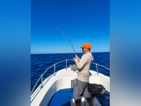An angler enjoys a day of fishing on the open ocean, showcasing the thrill of reeling in a catch from the comfort of a boat.