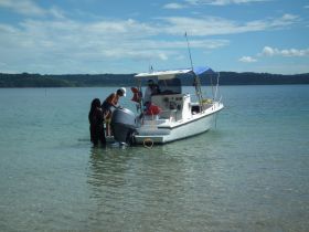 A group of individuals engages in activities on a boat in shallow waters, showcasing a fun day out on the water.