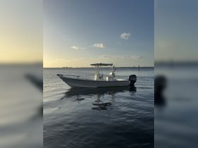 A sleek speedboat is anchored in calm waters, showcasing its clean lines and reflective surface against a serene sunset backdrop.