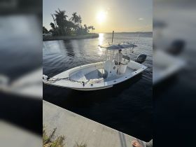 A sleek speedboat is docked at sunset, with a person preparing for an exciting day on the water. Perfect for fishing trips or leisurely cruises.