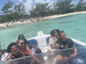 A lively group enjoys a day on the water, with a vibrant beach scene in the background — perfect for celebrations and fun outings.