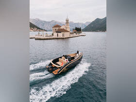 A couple enjoys a scenic boat ride past a picturesque island with a historic church, surrounded by stunning mountain views — a perfect backdrop for memorable adventures on the water.
