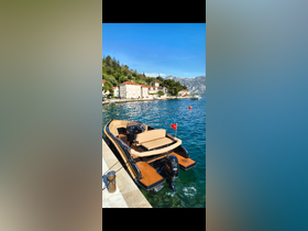 A sleek speedboat docked along a picturesque waterfront, showcasing its elegant design against a backdrop of charming coastal homes.