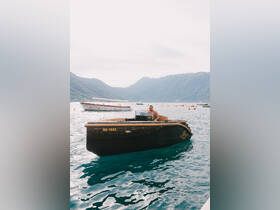 A man enjoys a scenic boat ride in a picturesque bay surrounded by mountains, showcasing the beauty of the water and landscape.