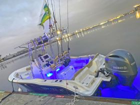 A sleek center console fishing boat docked at twilight, showcasing its modern design and illuminated features, perfect for evening fishing trips.