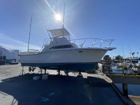 A striking view of a yacht docked and lifted on stands, showcasing its sleek design against a clear blue sky — perfect for boat enthusiasts and potential buyers.